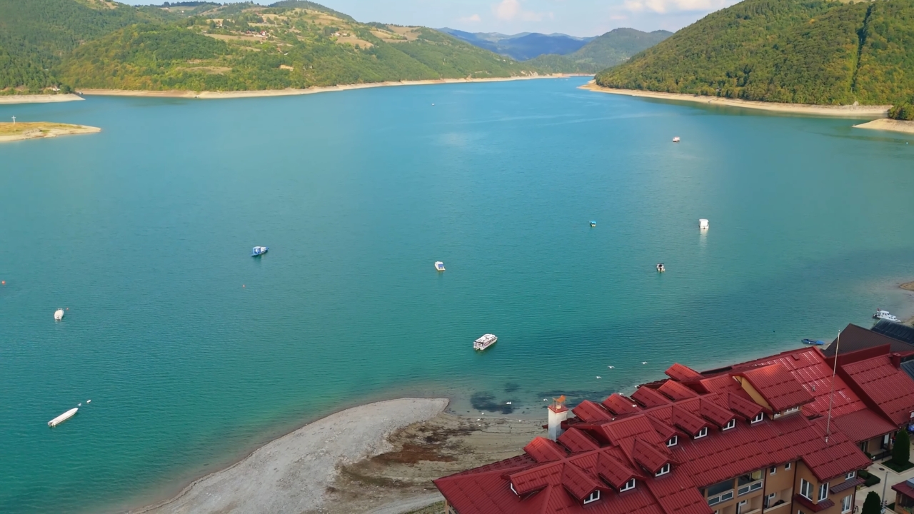 Pogled na Uvac i čamce na mirnoj vodi okruženoj planinama