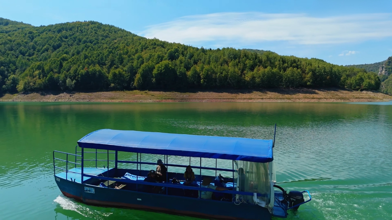 Čamac sa turistima prolazi mirnim delom Uvca okruženim šumom