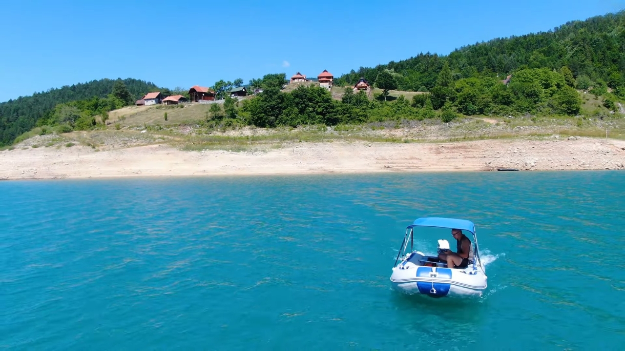 Čamac na mirnom jezeru Zaovine tokom sunčanog letnjeg dana