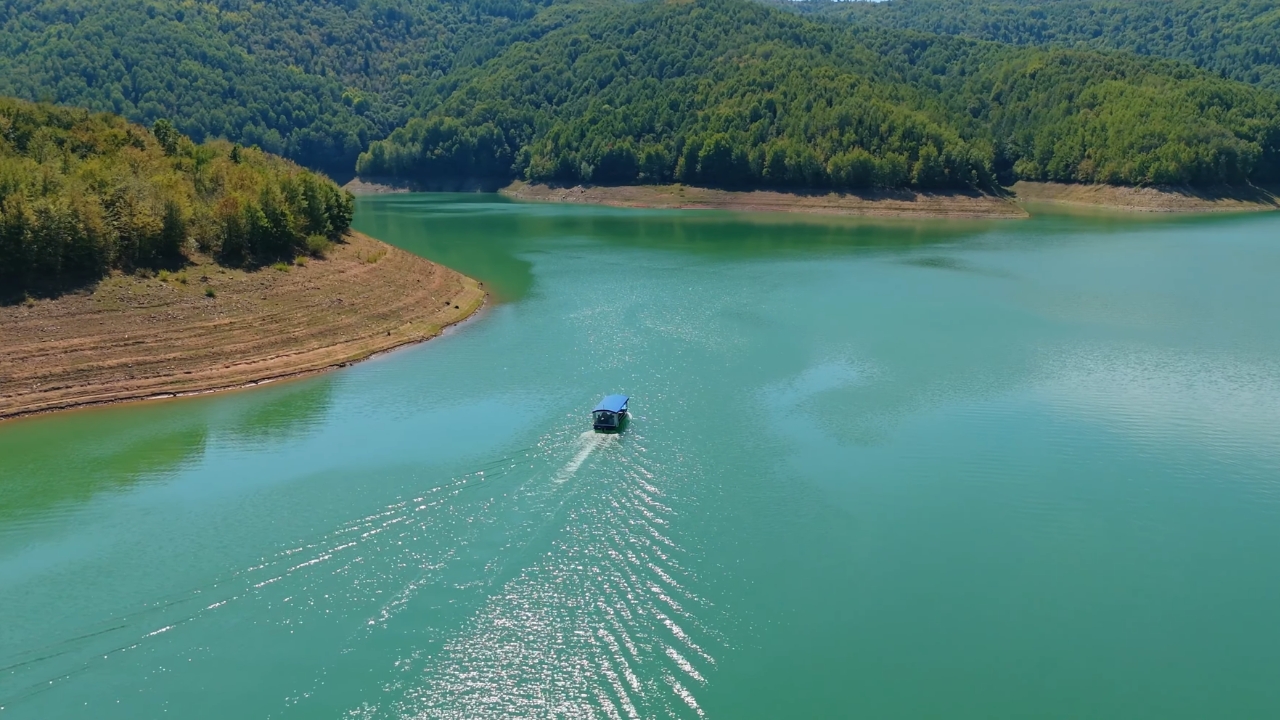 Čamac prolazi kroz mirni deo Uvca okružen šumom i zelenim brdima